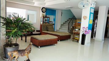 A spacious living area with a sofa set, a potted plant, a decorative horse statue, and a staircase leading to an upper floor.
