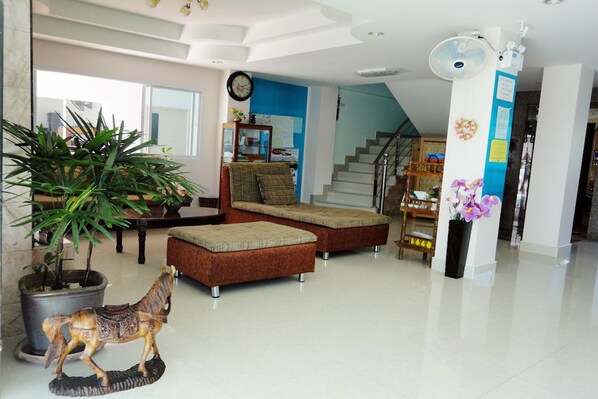 A spacious living area with a sofa set, a potted plant, a decorative horse statue, and a staircase leading to an upper floor.