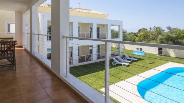 En moderne lejlighed med balkon, swimmingpool og udsigt til en nabobygning.