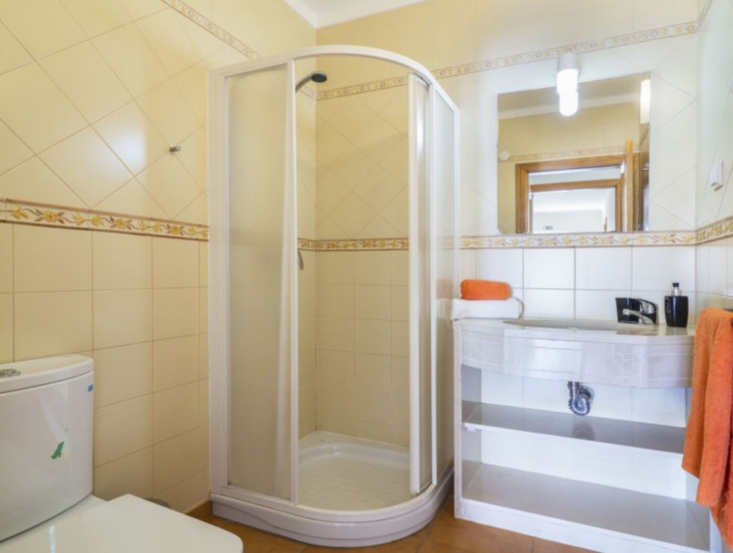 Ein Badezimmer mit Dusche, Toilette, Waschbecken und Spiegel.