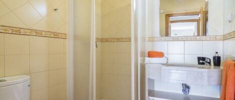 A bathroom with a shower, toilet, sink, and mirror.