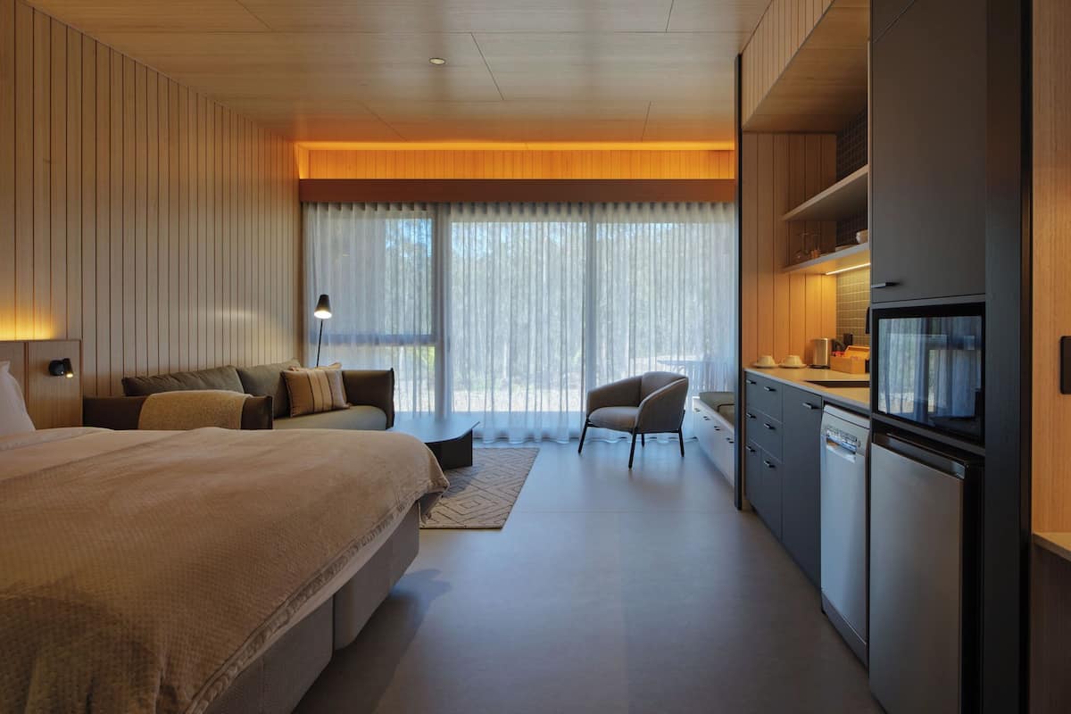Une chambre d’hôtel moderne équipée d’un grand lit, d’un bureau et d’une kitchenette.
