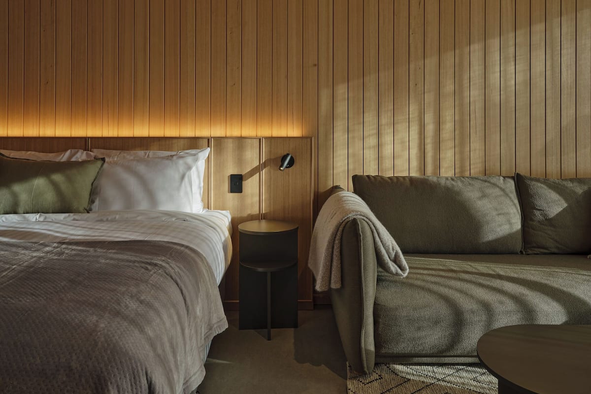 Une chambre à coucher avec un lit, une table de chevet, une lampe et un canapé.