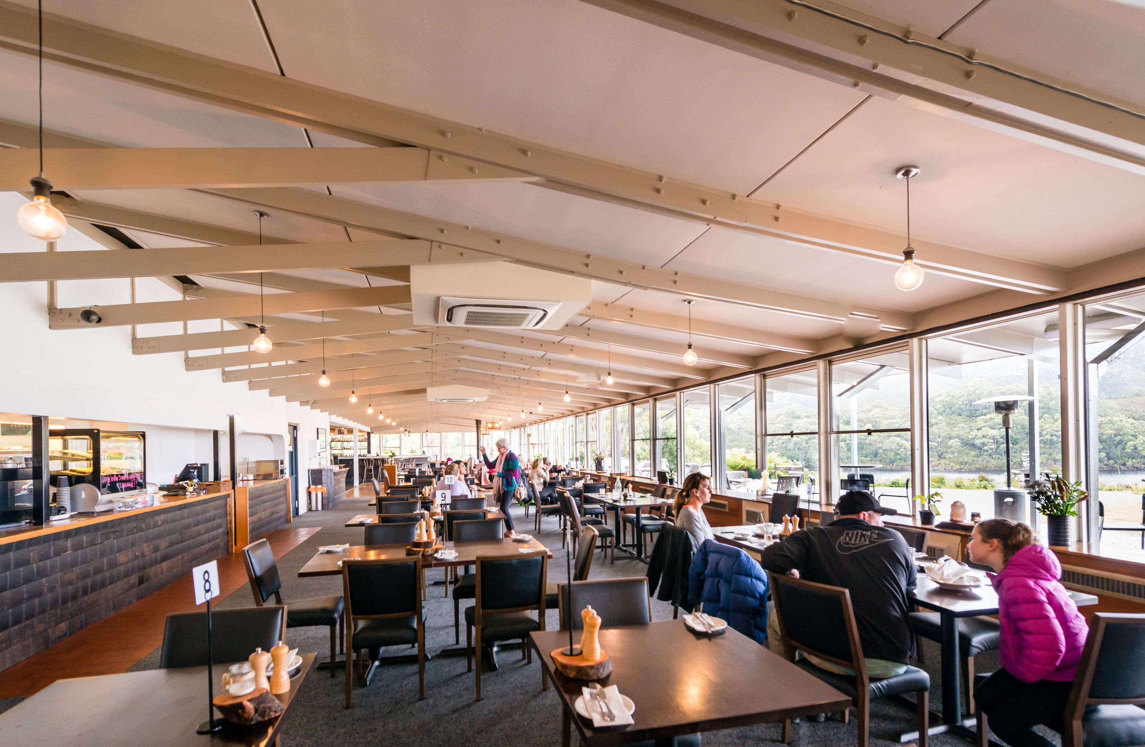 Un'ampia sala ristorante con soffitti alti e ampie finestre che offrono vista sull'esterno.