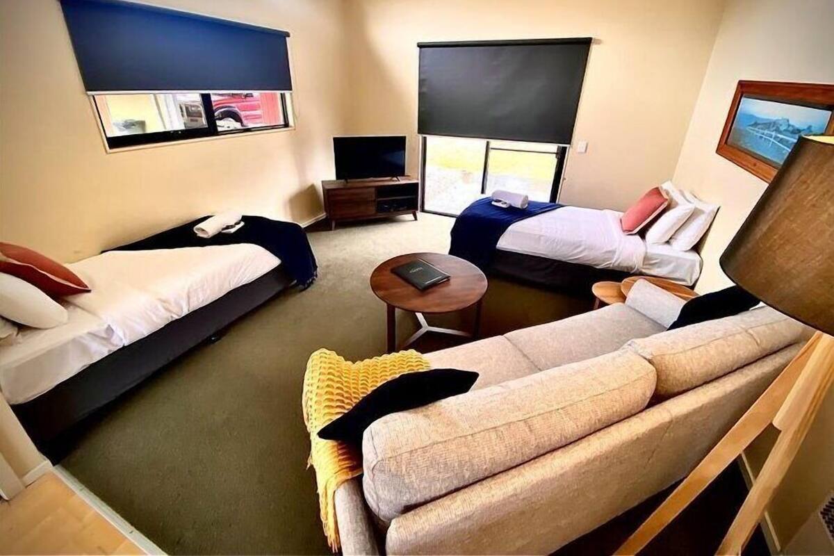 Une chambre d’hôtel de taille réduite, comprenant deux lits simples, un canapé, une petite table et un téléviseur.