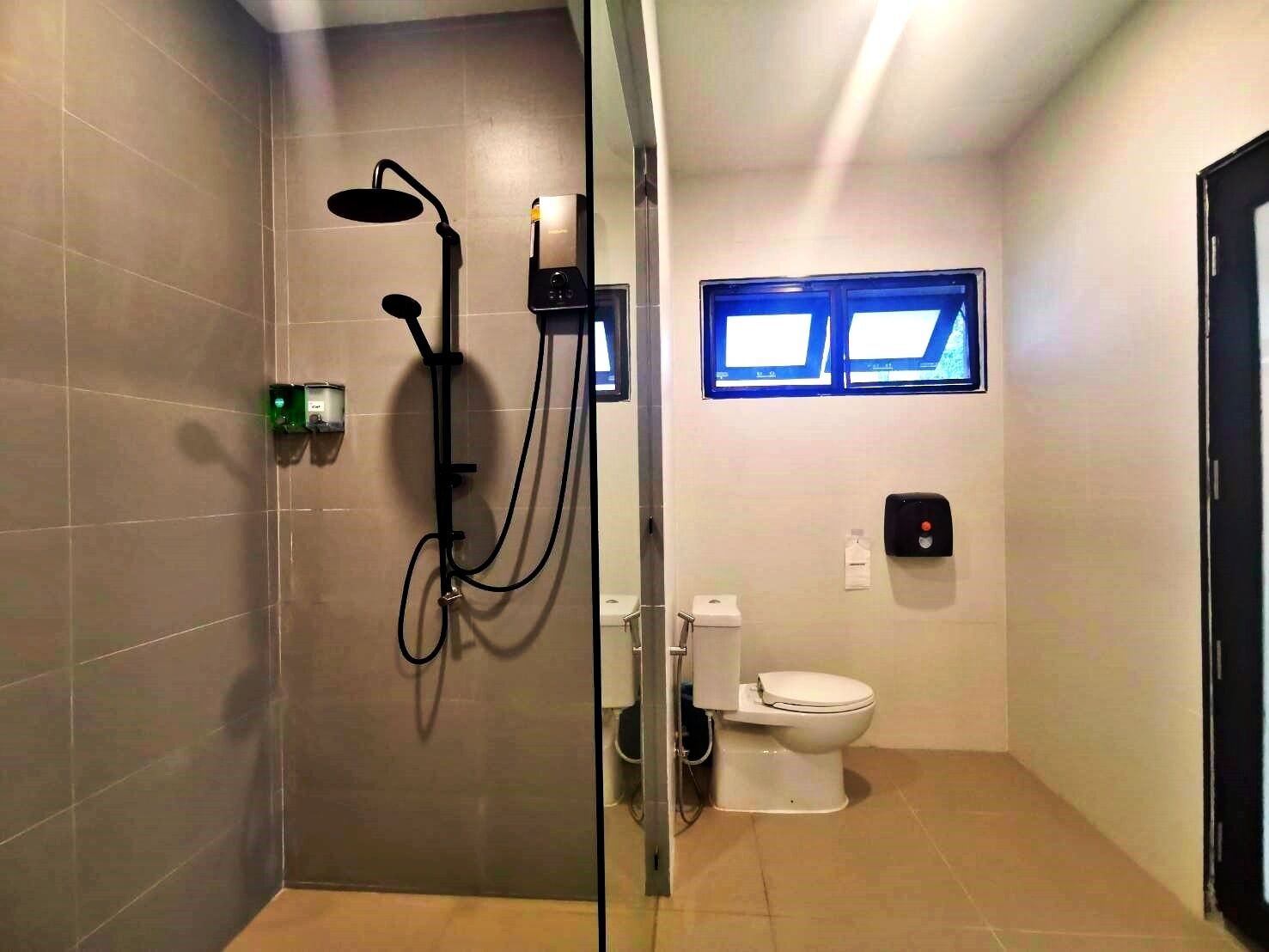 A bathroom with a shower, toilet, and a window.