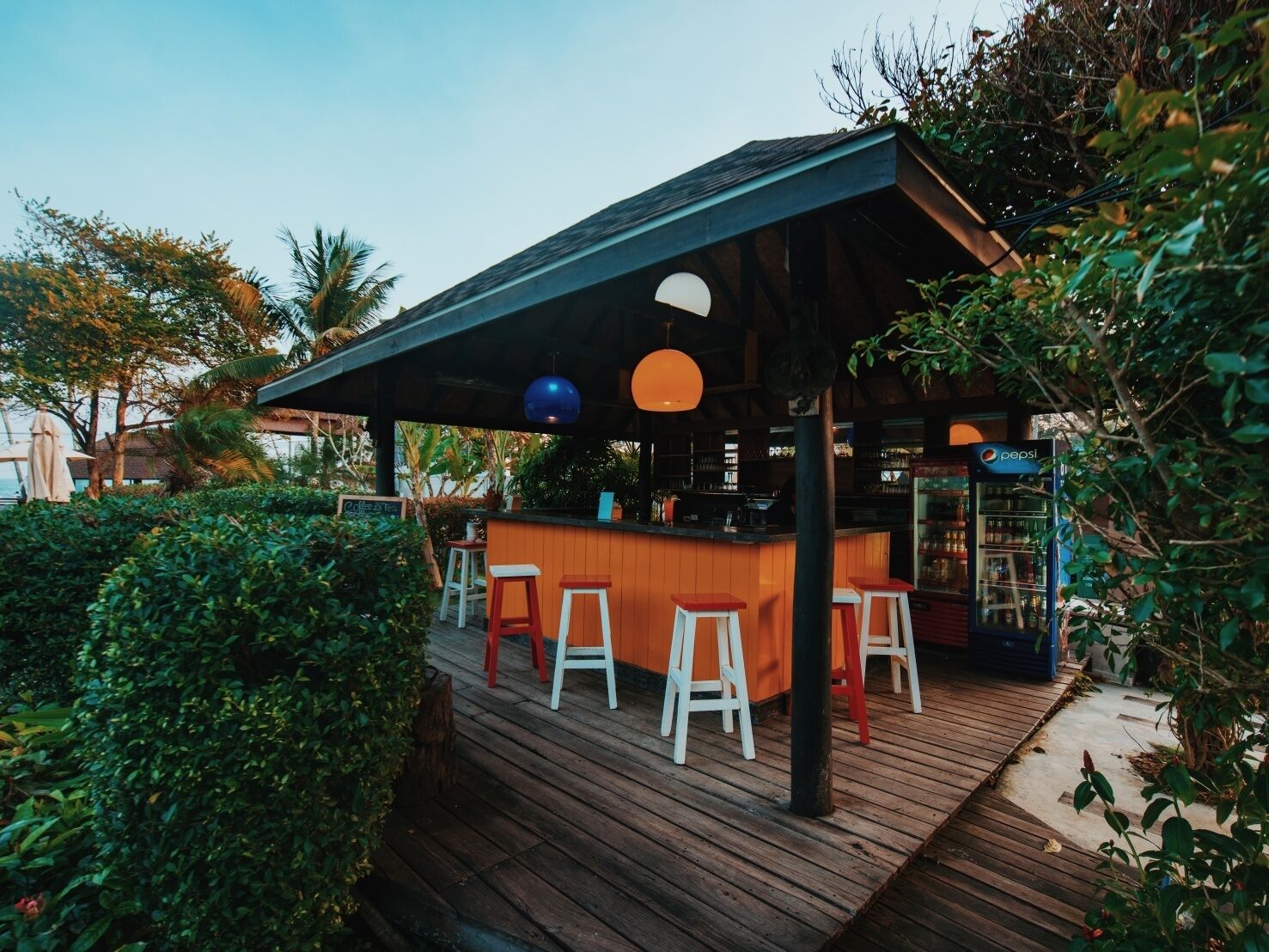 A wooden deck with a bar area, stools, and a Pepsi refrigerator.