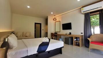 A hotel room with a bed, a desk, a chair, a television, and an air conditioning unit.