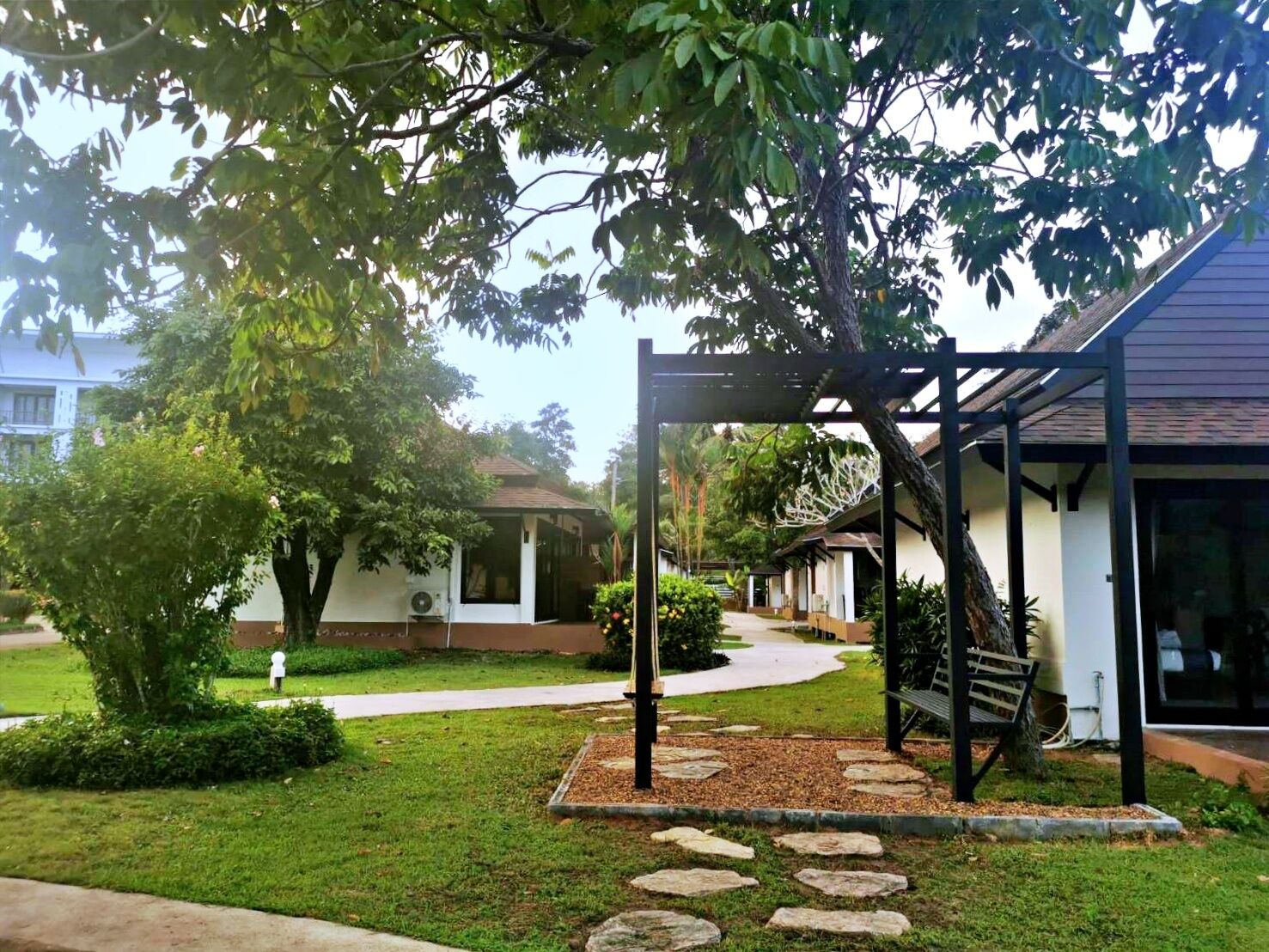 Un patio con pérgola, sendero de piedra y una banca.
