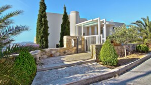 Un bâtiment moderne doté d’une entrée en pierre, d’un patio couvert et d’une vue sur la mer.