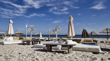 Een privéstrand, ligstoelen aan het strand, parasols, strandlakens