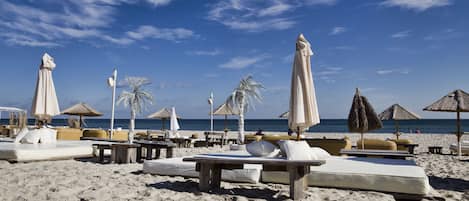 Een privéstrand, ligstoelen aan het strand, parasols, strandlakens