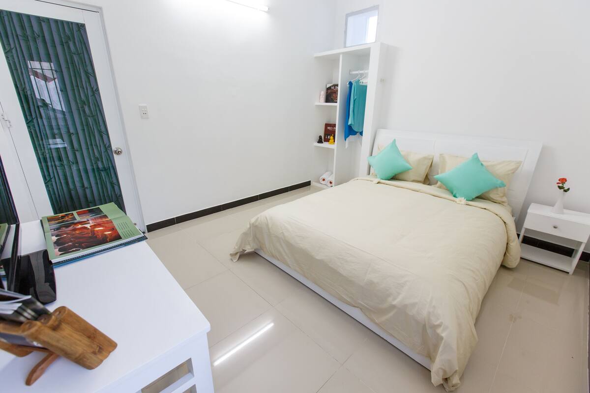 A bedroom with a bed, bedside tables, a wardrobe, and a desk with a chair.