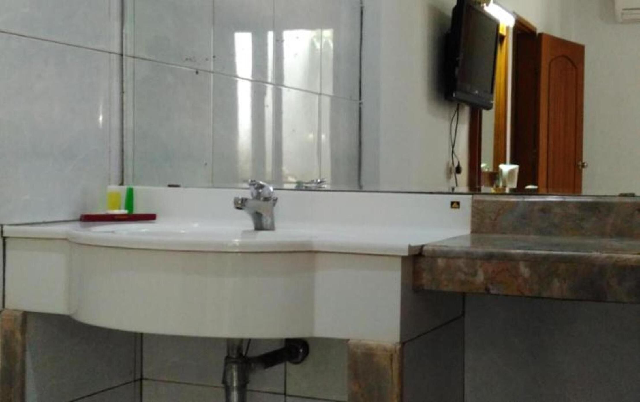 A bathroom with a white sink, a mirror, and a wooden door.