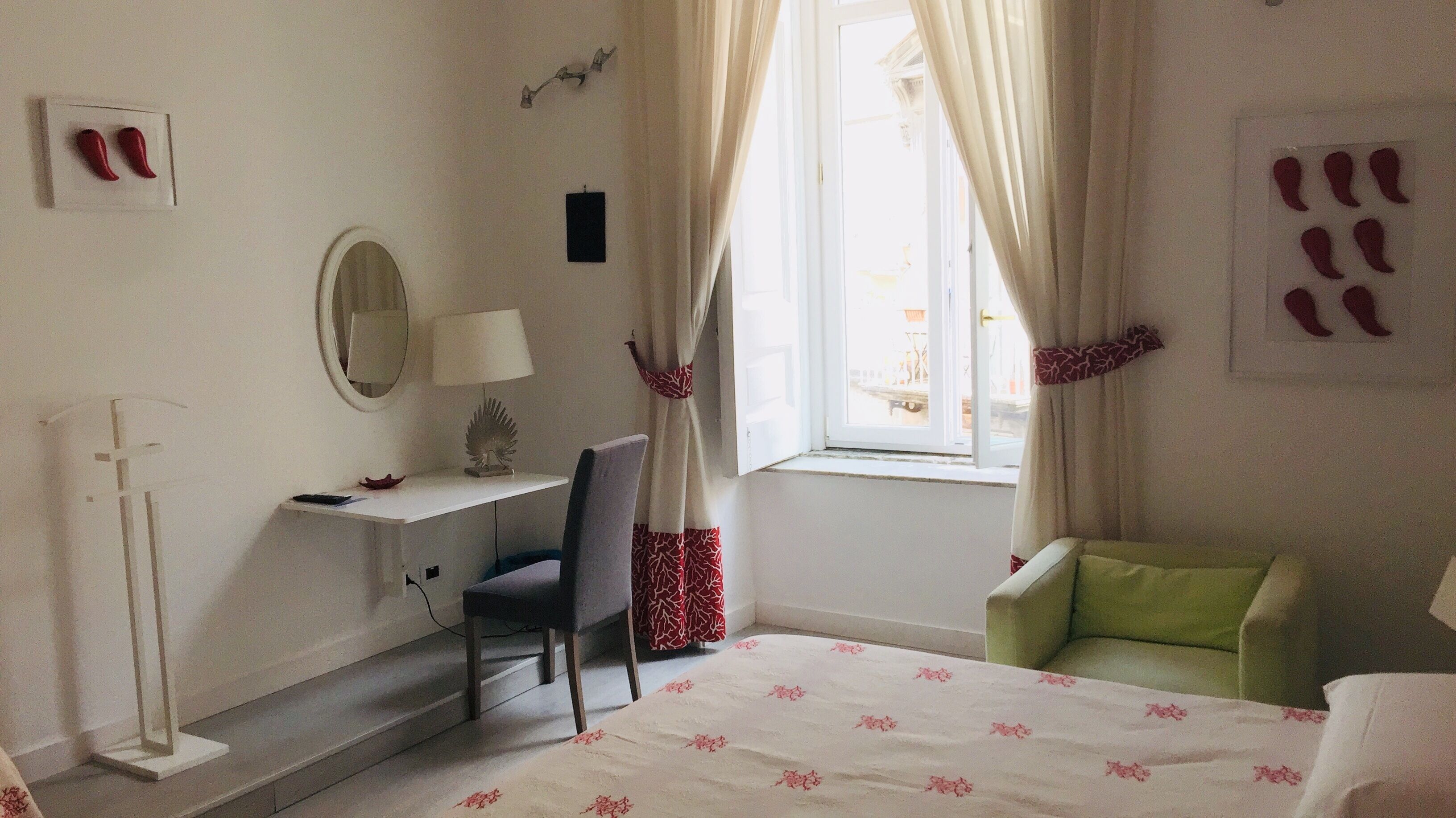 Un dormitorio con cama, un escritorio con silla, un espejo y una ventana con cortinas.
