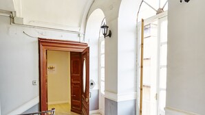 Un pasillo con puerta de madera, una lámpara y una escalera.