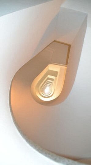 Un escalier en colimaçon avec un luminaire central.