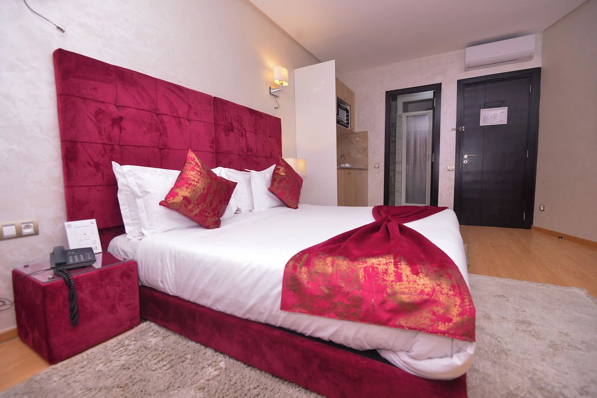 Habitación de hotel con una cama grande, un teléfono en la mesita de noche y una puerta con un cartel.