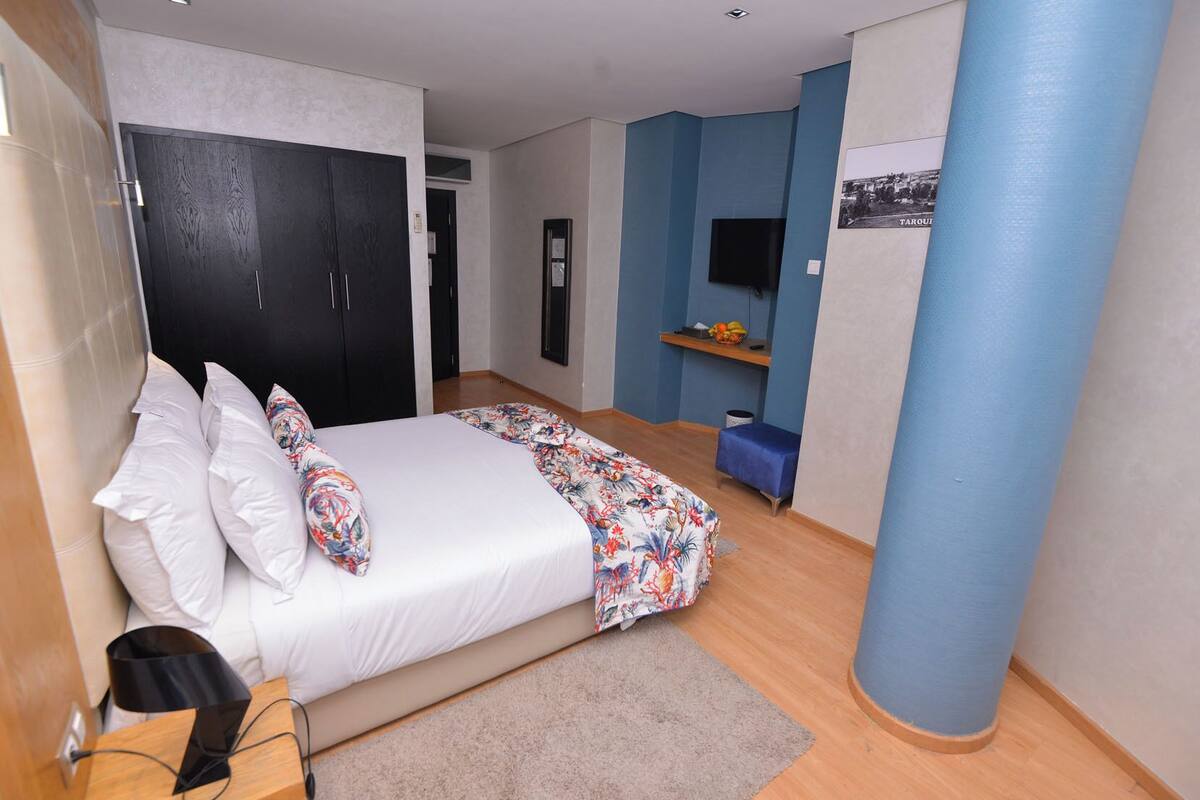 Un dormitorio con cama, escritorio, silla, televisor y armario.