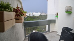 Un balcón con vistas a edificios, una silla y una pequeña mesa.
