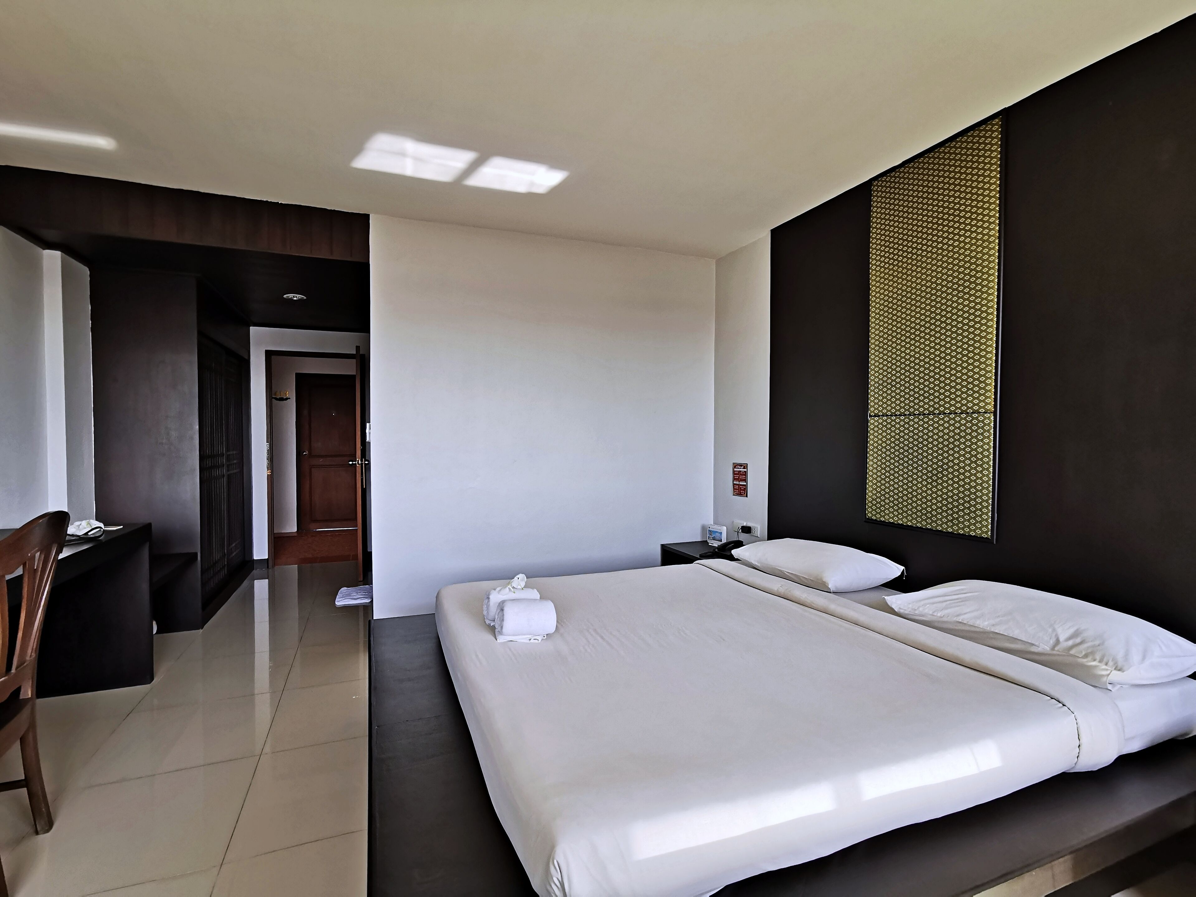 Quarto de hotel moderno com uma cama grande, uma escrivaninha e uma cadeira.