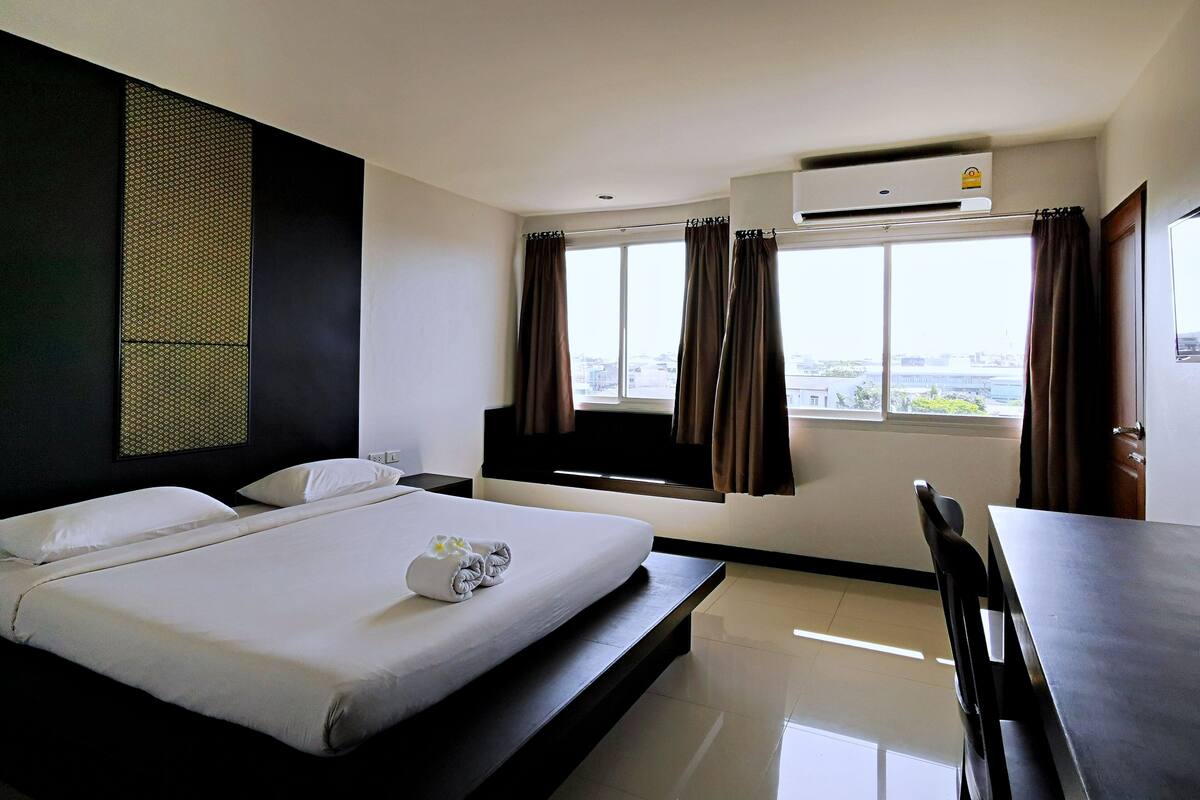 A hotel room with a bed, a desk, and a window with curtains.