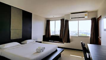 Una habitación de hotel con cama, escritorio y ventana con cortinas.