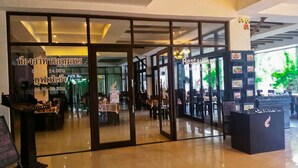 Un restaurant avec des portes vitrées, un comptoir noir orné d’un logo et des tableaux encadrés accrochés au mur.