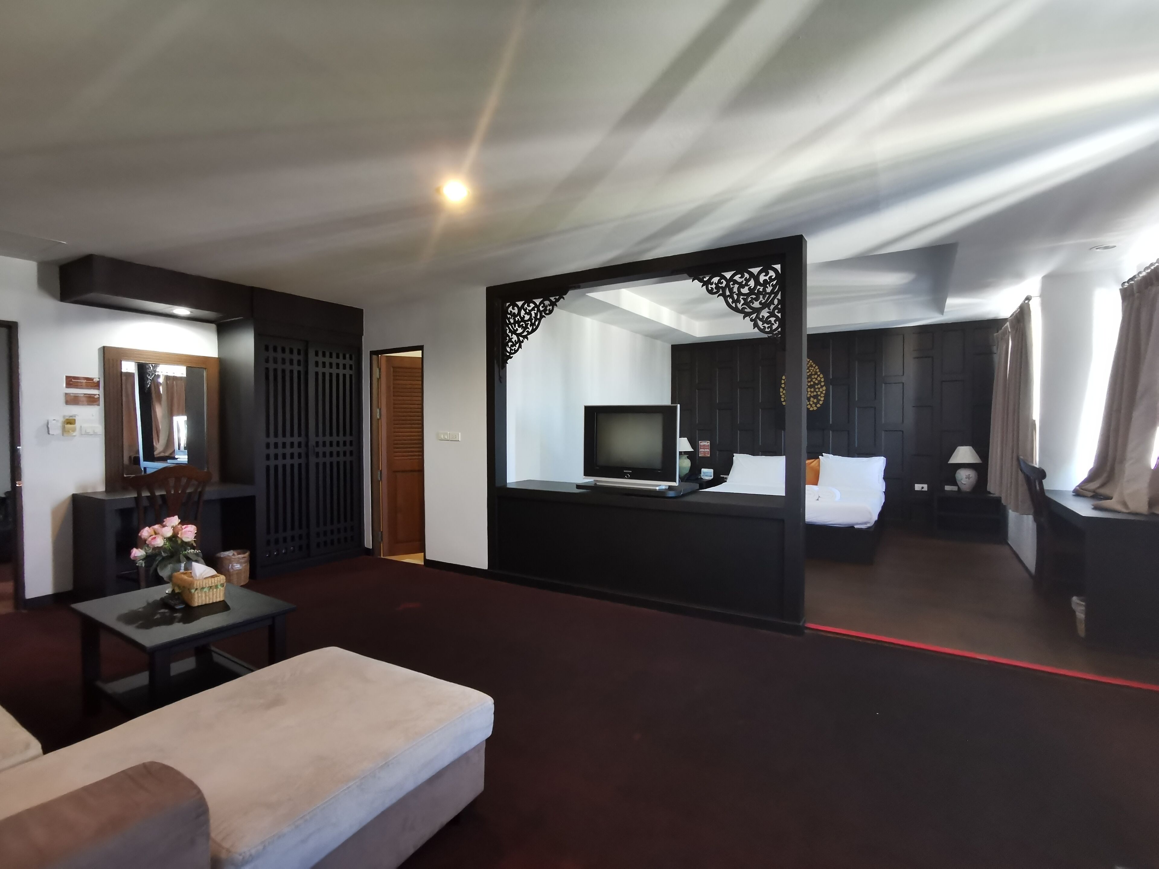 Una habitación de hotel con una cama, televisión, escritorio y zona de estar.