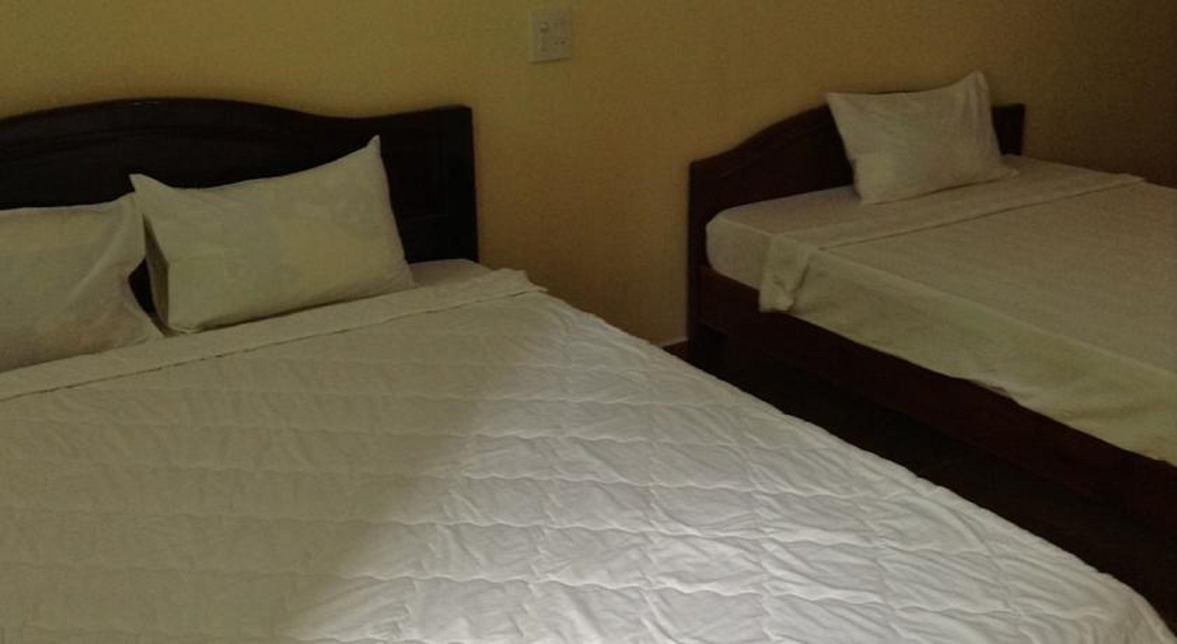 Two single beds with wooden headboards and white bedding in a room with beige walls.
