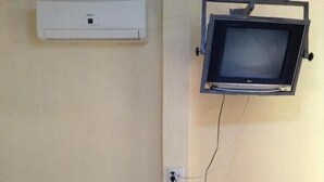 A room with a wall-mounted air conditioner, a television, and a Midea refrigerator.