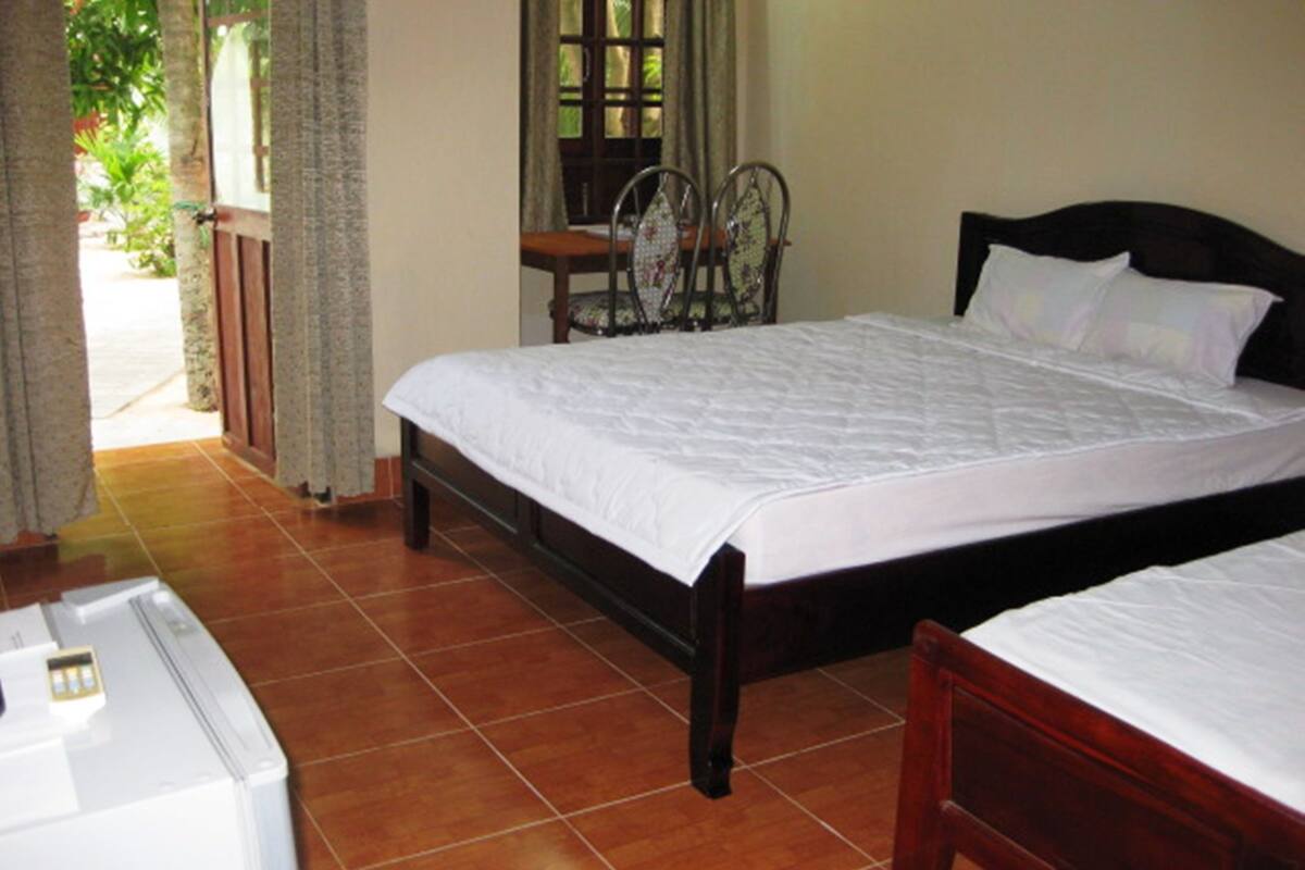 Un dormitorio con dos camas, un aparador de madera y una ventana con cortinas.