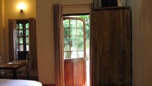A room with a bed, a desk, a cabinet, and a window with curtains.