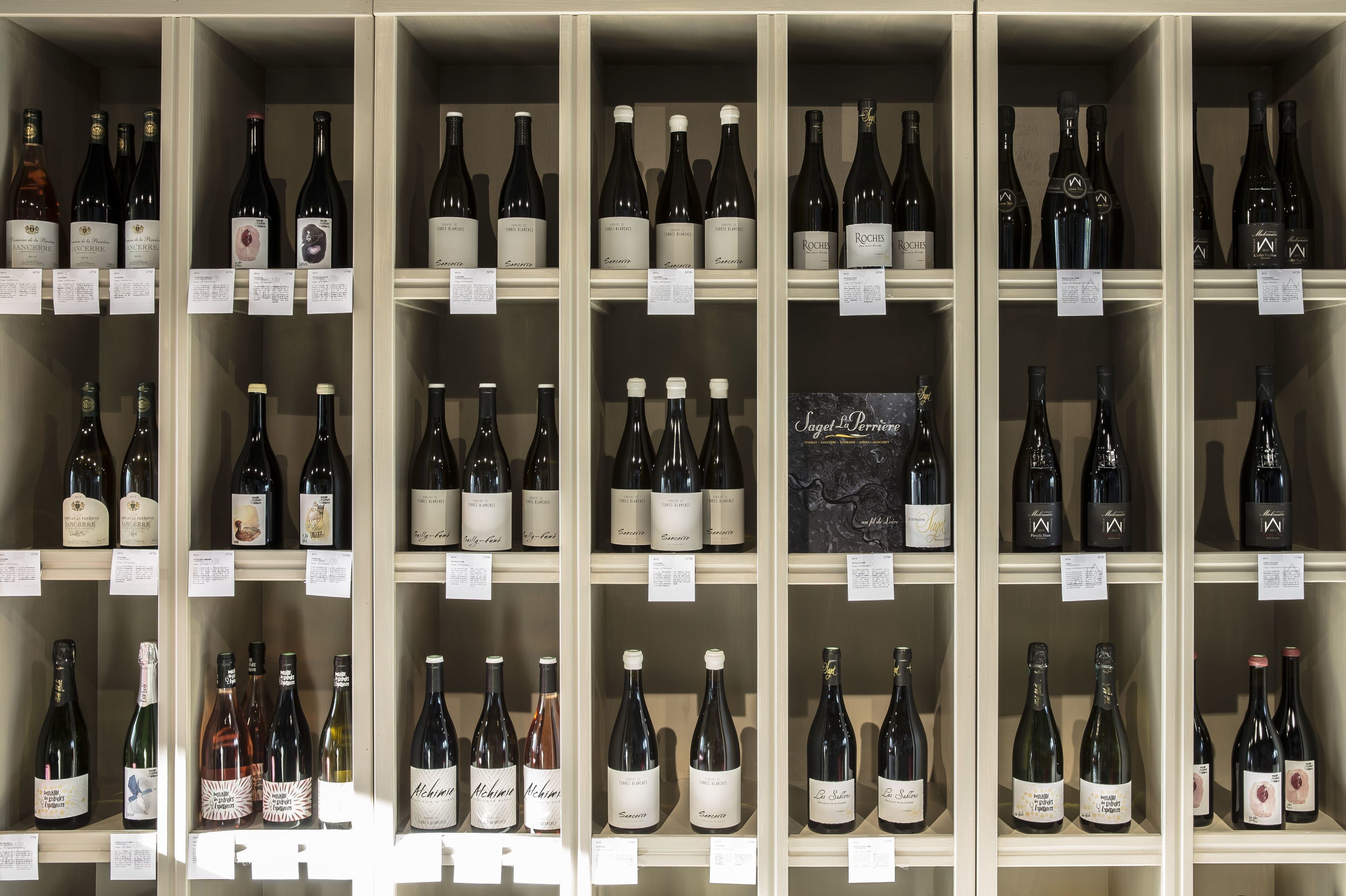 Una bodega con varias botellas de vino, cada una con etiqueta y precio.