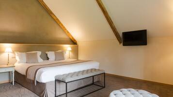 A bedroom with a large bed, bedside lamps, a flat-screen TV, and a wooden ceiling.