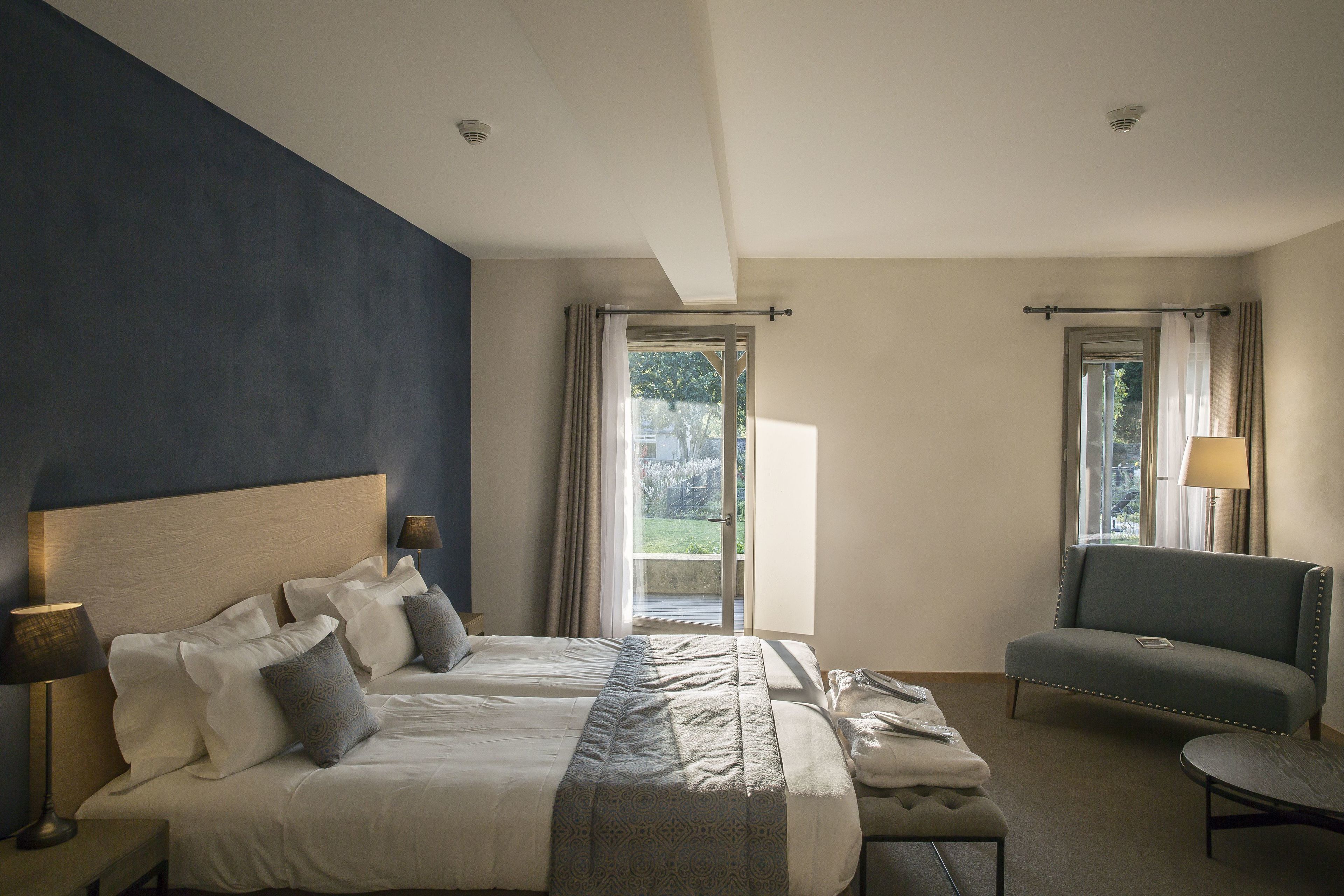 Habitación de hotel con dos camas, un sofá, una mesa y vistas al exterior.