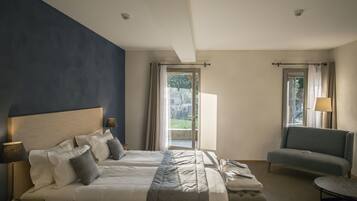 Habitación de hotel con dos camas, un sofá, una mesa y vistas al exterior.