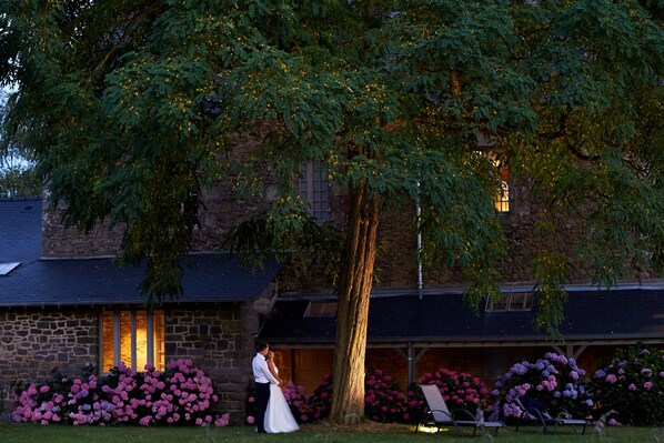 A stone building with a large tree in front.