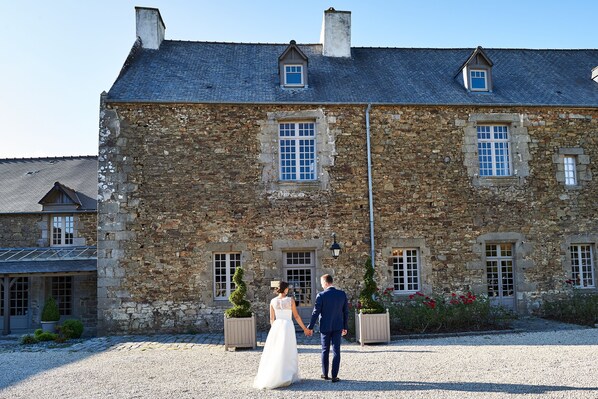 A stone building with multiple windows and a gravel driveway.