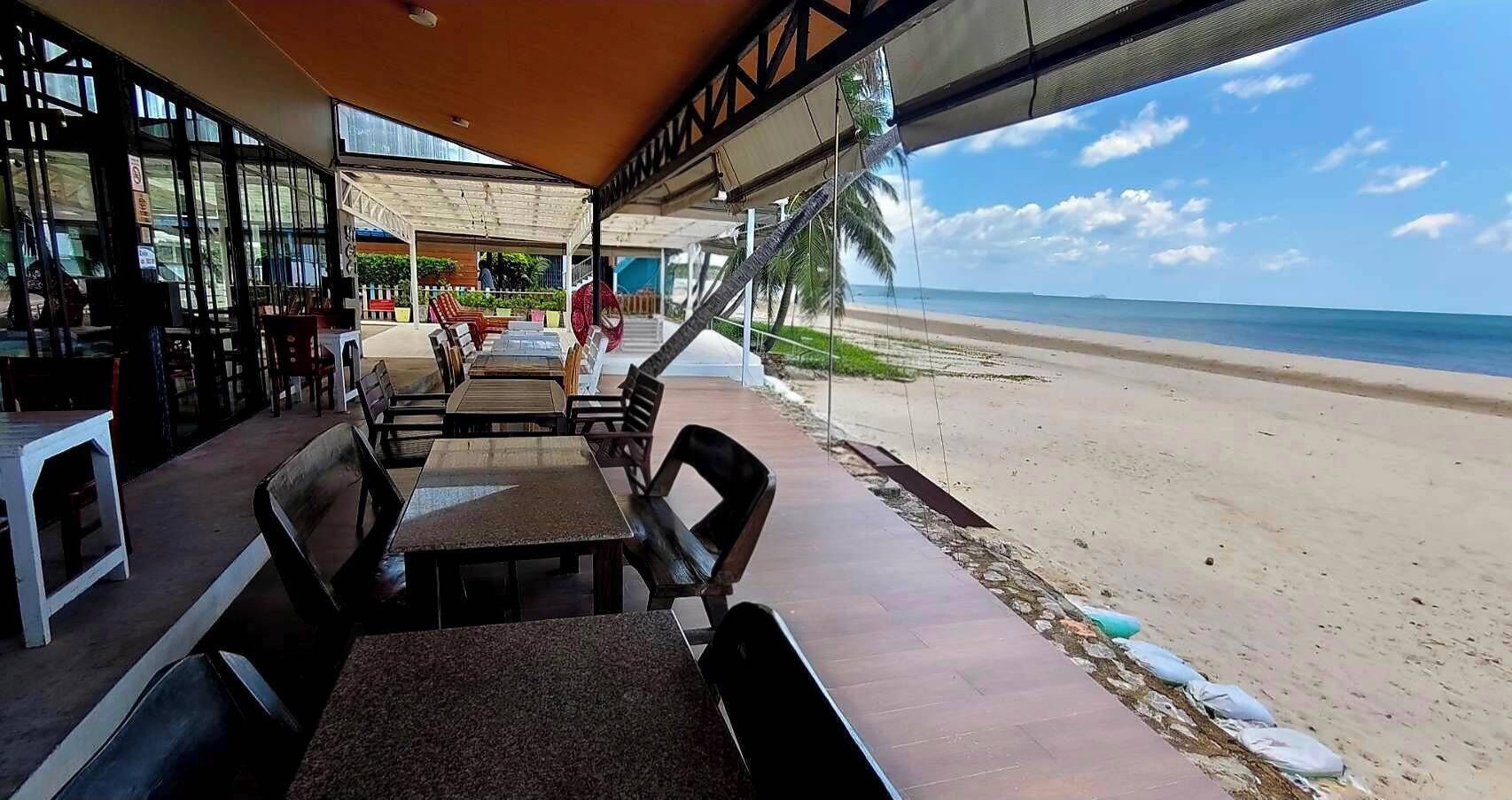 Un espace extérieur aménagé avec des tables et des chaises, offrant une vue sur la plage.