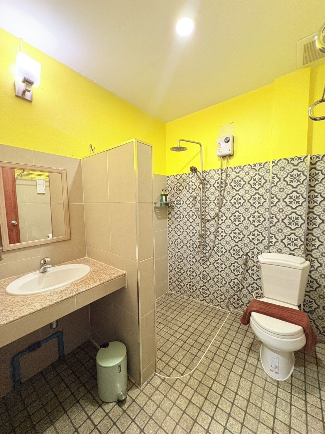 Een badkamer met een wastafel, spiegel, toilet, douche en betegelde vloer.