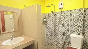 Een badkamer met een wastafel, spiegel, toilet, douche en betegelde vloer.