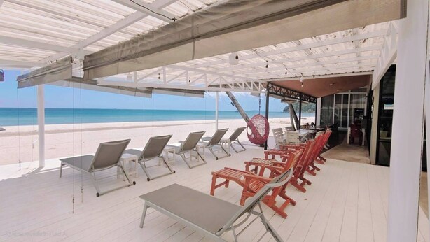 Un salon de plage doté de chaises longues et d’un espace de détente abrité, offrant une vue sur l’océan.