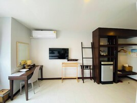 Habitación de hotel compacta con escritorio, silla, televisor, armario y una pequeña mesa.