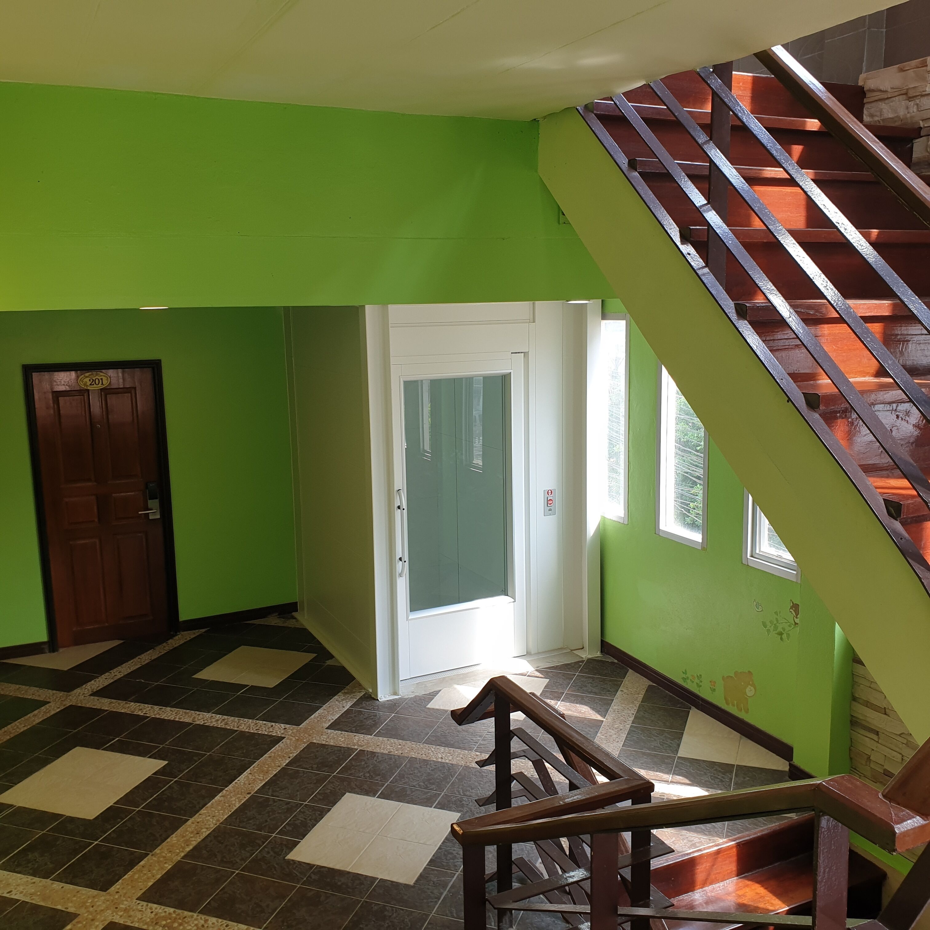 A room with green walls, a wooden door, a white door, a staircase, and a tiled floor.