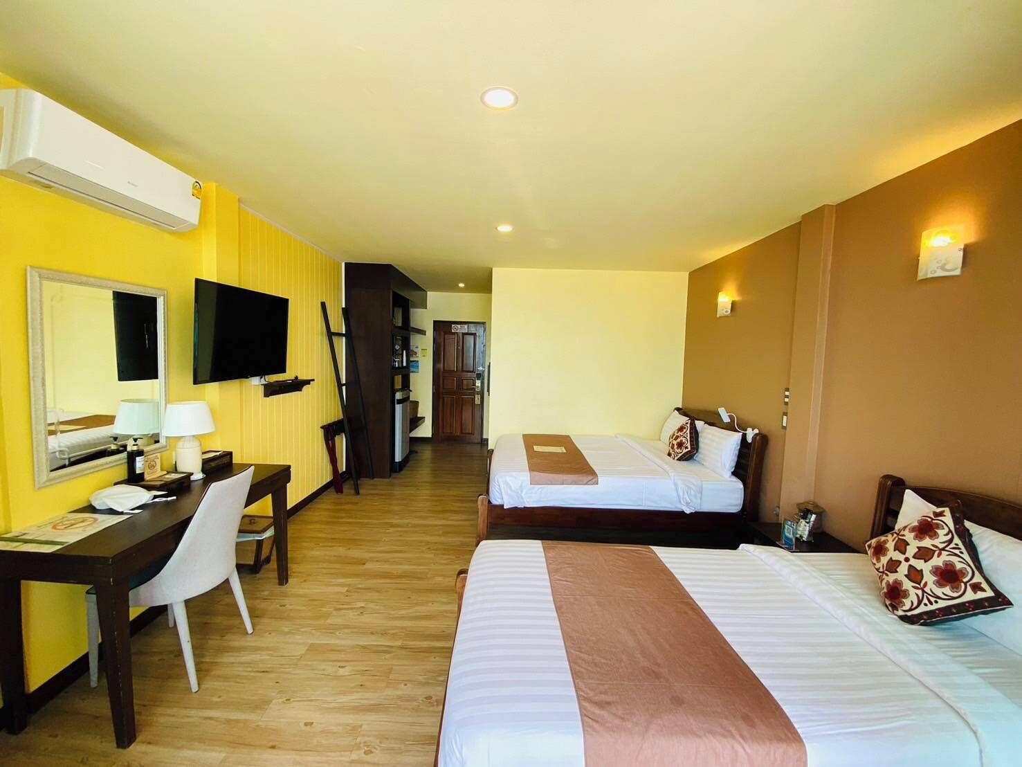 Une chambre d’hôtel avec deux lits, un bureau avec une chaise, une télévision et un miroir.