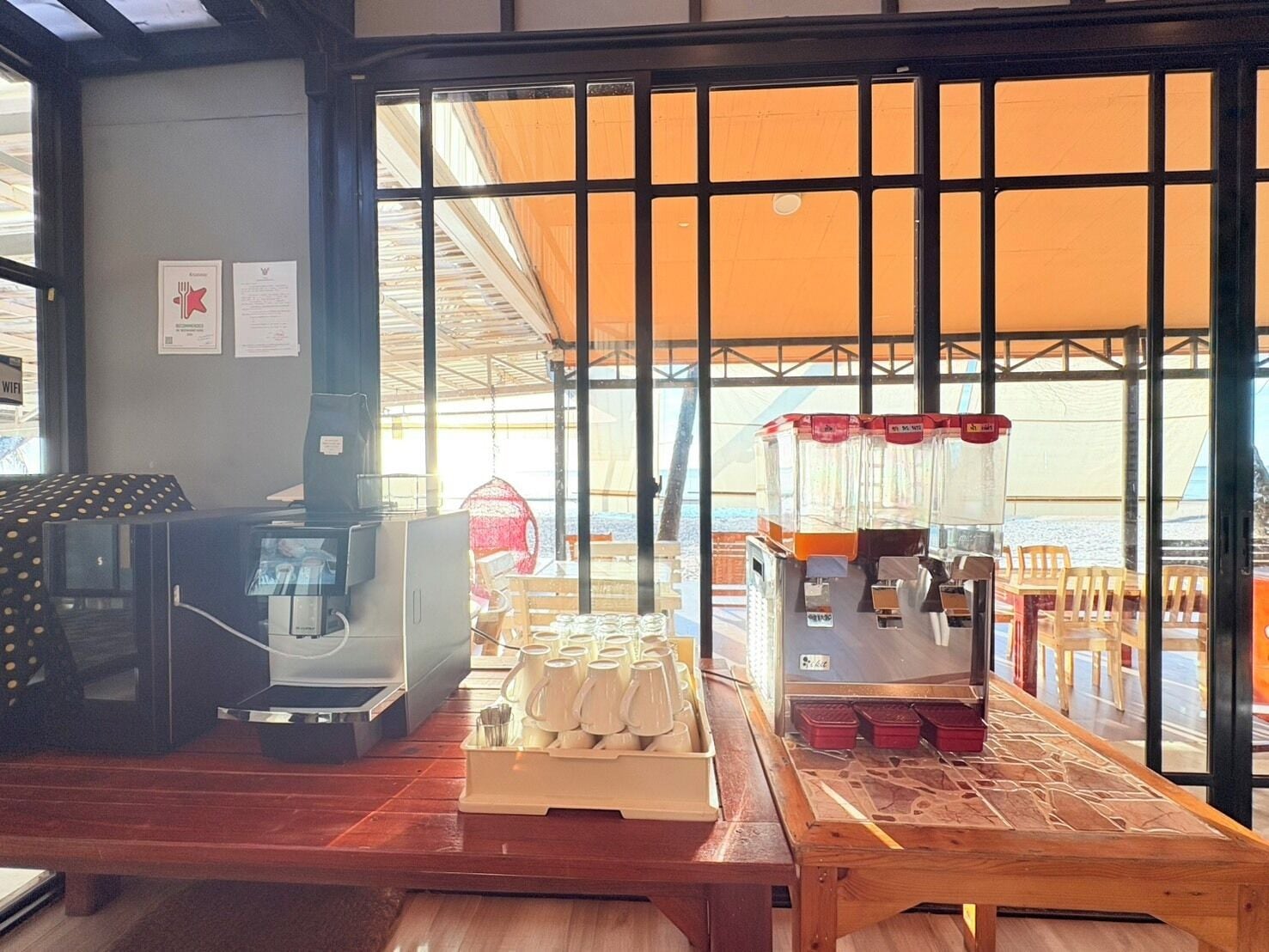 A coffee shop interior with a wooden counter, coffee machines, and a view through large windows.
