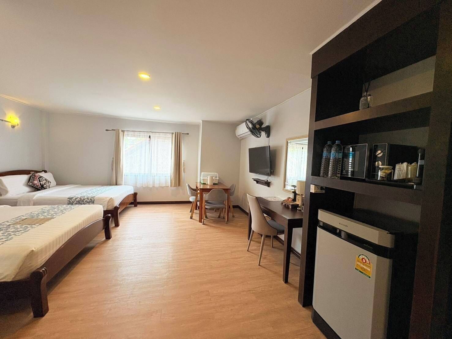 Una habitación de hotel con dos camas, un escritorio con silla, televisor y un minibar.