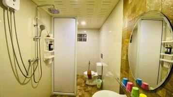 A bathroom with a shower, toilet, sink, and a mirror.