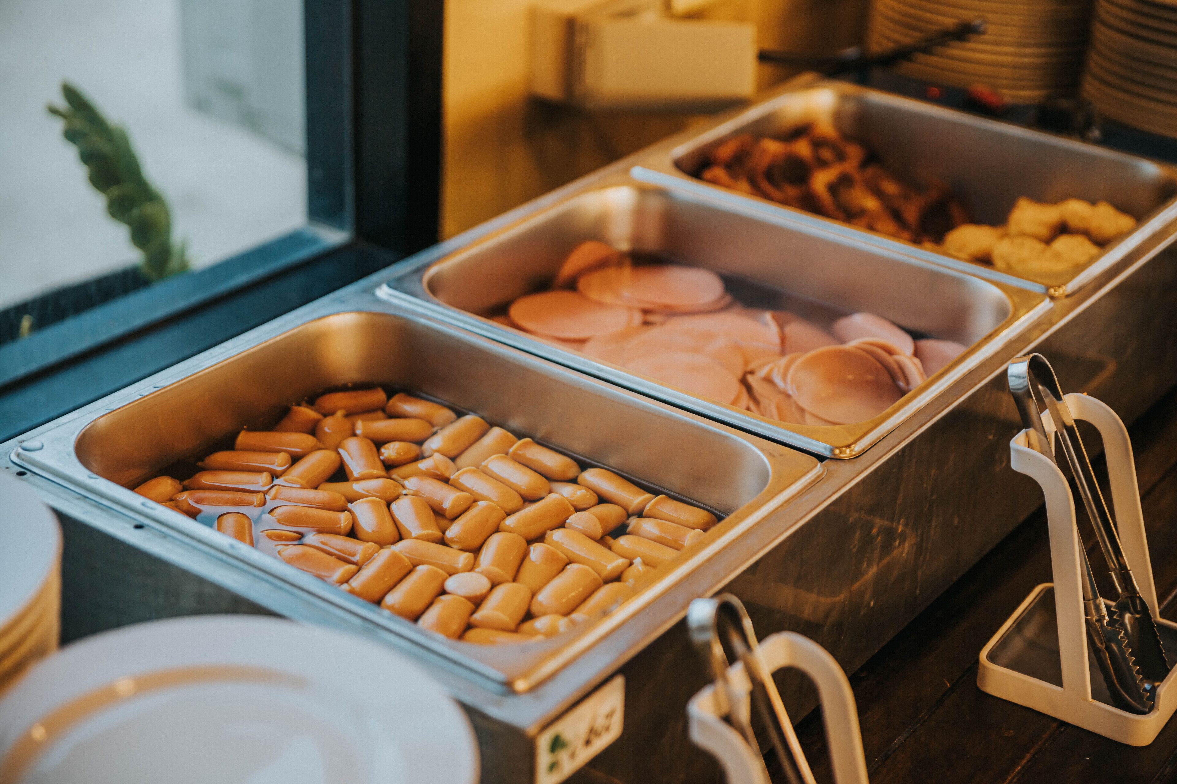 A buffet with various food items including sausages and pastries.